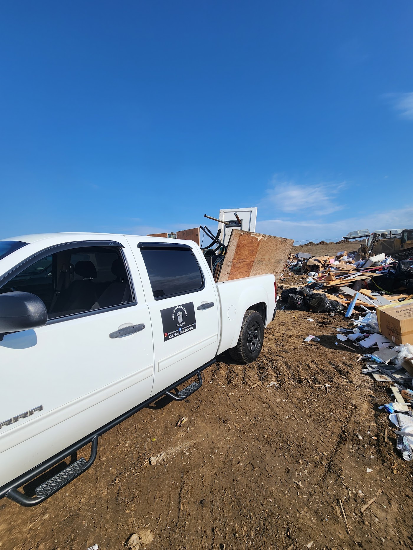 Truck backed up to a pile of demolition debris in a yard