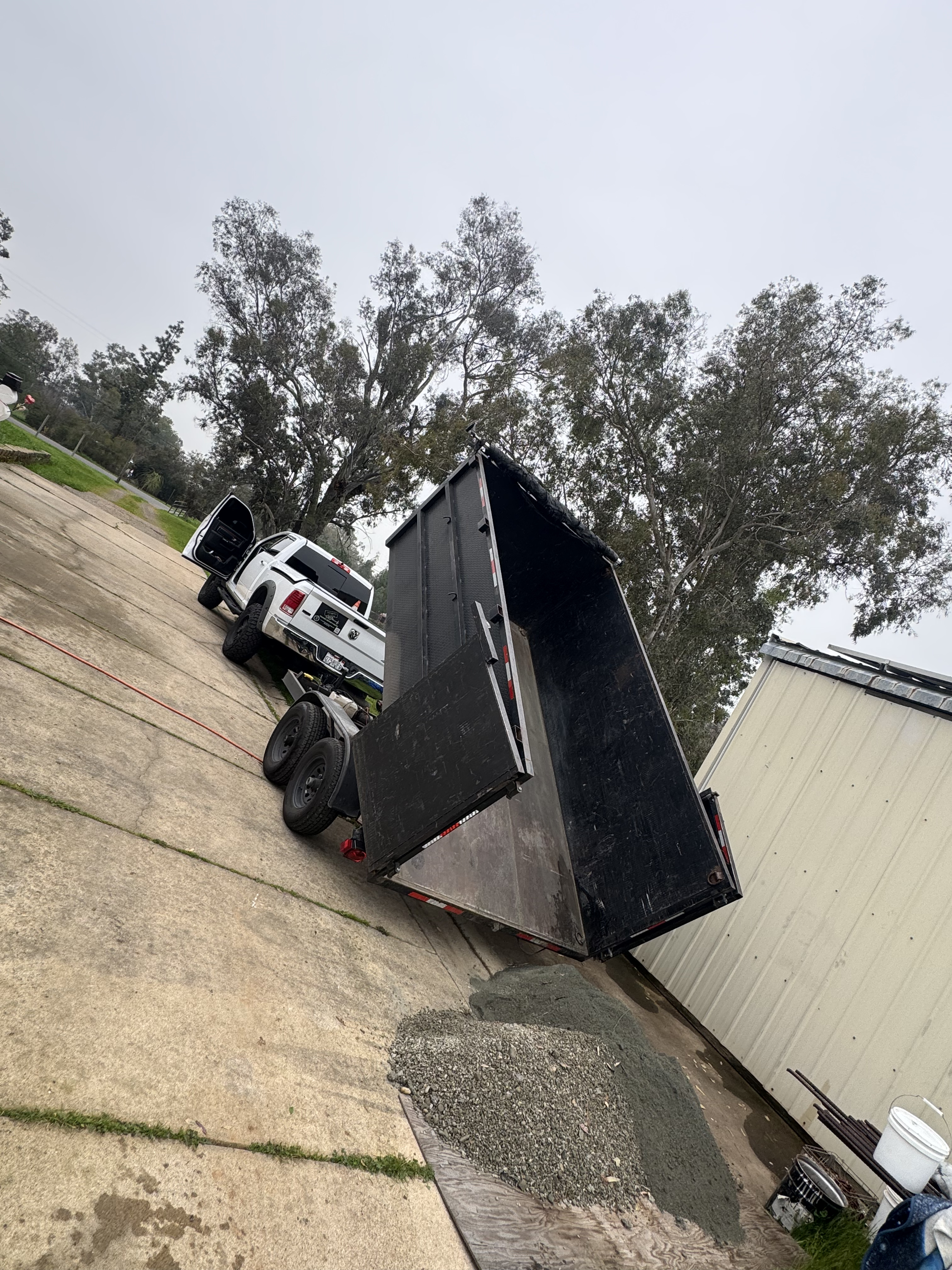 Dump trailer tipped up unloading gravel from a driveway